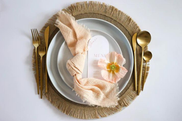 top view of a table setup with a fringed natural rattan placemat