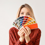 young woman on white background holding colour palette cards