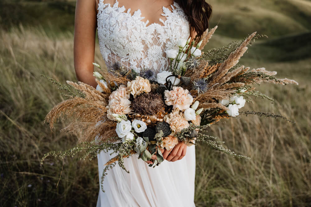 boho bride holding bouquet of dried flowers and grass