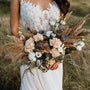 boho bride holding bouquet of dried flowers and grass