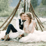 bride and groom on the ground in front of teepee wedding altar