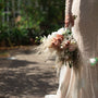 bride in wedding dress with intricate designs holding bouquet downwards
