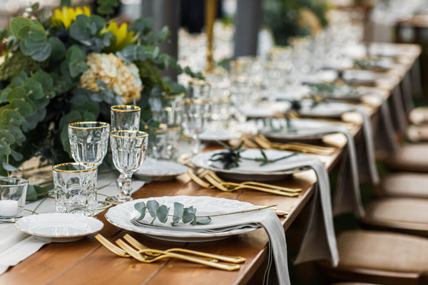 wedding reception table with green theme and gold cutlery